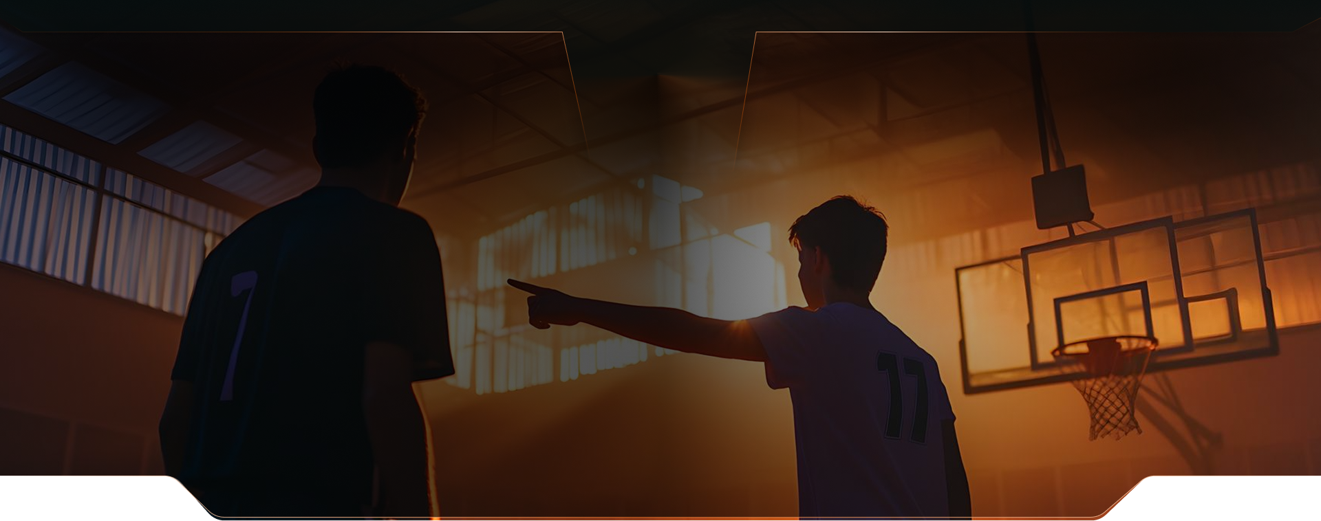 Two basketball players on an indoor court at sunset